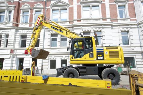 The Komatsu PW118 wheeled excavator working in an urban construction site, highlighting its compact size and maneuverability
