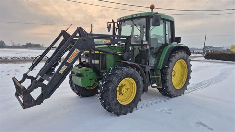 Zdjęcie przedstawiające nowoczesny ciągnik John Deere z zamontowanym ładowaczem czołowym serii M podczas pracy