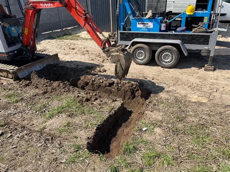 Minikoparka pracująca na wąskiej działce budowlanej, wykonująca precyzyjny wykop.