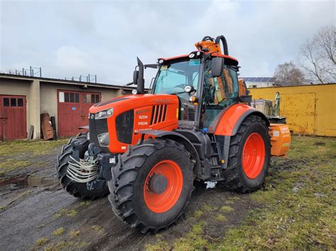 Fotografia ciągnika Kubota M7-153 z zamontowanym ramieniem wysięgnikowym pracującym przy rowie