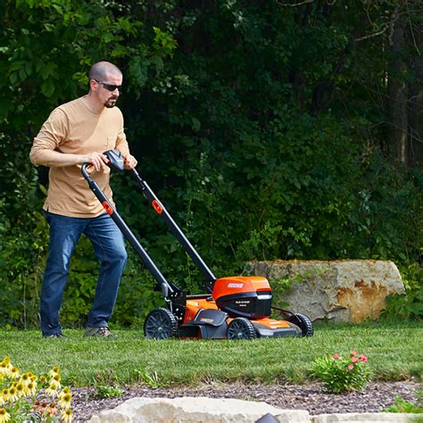 The Husqvarna M 145 petrol lawnmower in action, cutting grass on a small lawn.