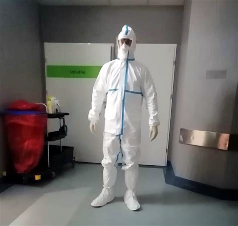 Osoba w pełnym stroju ochronnym (PPE) z opryskiwaczem plecakowym podczas dezynfekcji pomieszczenia