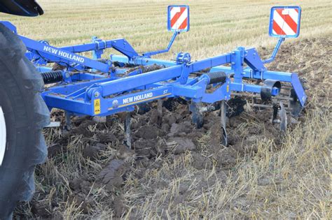 Thematic photo of a field after harvesting, with a kultywator podorywkowy in operation