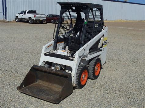 Zdjęcie przedstawiające wnętrze kabiny Bobcat 453 z widoczną plątaniną przewodów hydraulicznych