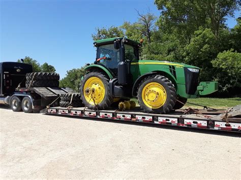 Thematic photo of a large agricultural tractor being loaded onto a low-loader trailer for transport