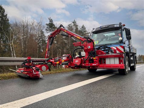 Zdjęcie przedstawiające nowoczesną kosiarkę czołową pracującą na polu w połączeniu z ciągnikiem rolniczym