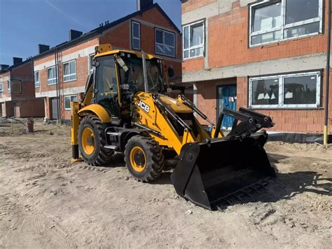 Zimowy krajobraz z pracującą koparko-ładowarką JCB 3CX z zamontowanym pługiem śnieżnym