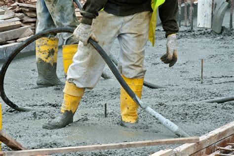 Thematic photo of a construction site with concrete pouring, showing a vibrator head in action