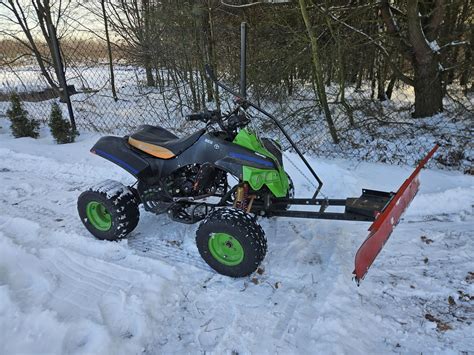Quad z zamontowanym plastikowym pługiem śnieżnym w akcji