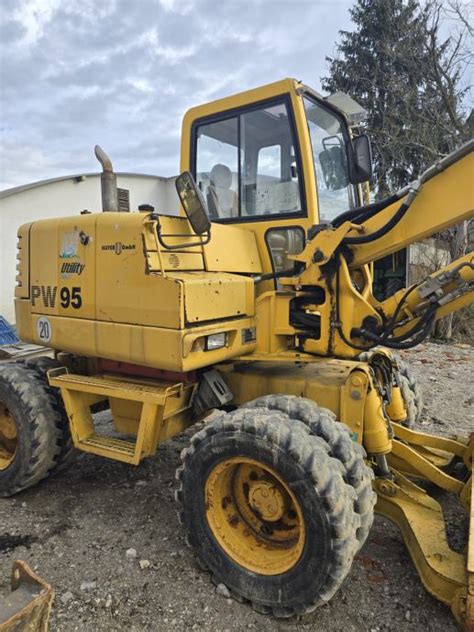 Fotografia przedstawiająca koparkę kołową Komatsu PW95 lub PW98 w trakcie pracy na placu budowy
