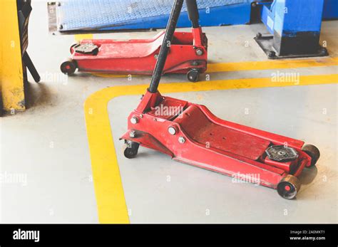 Thematic photo of a sturdy hydraulic jack in a workshop setting, possibly lifting a car
