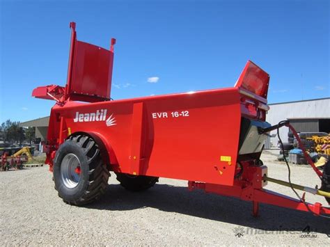 The Jeantil EVR tandem manure spreader operating in a field, showing its robust construction and wide spread pattern
