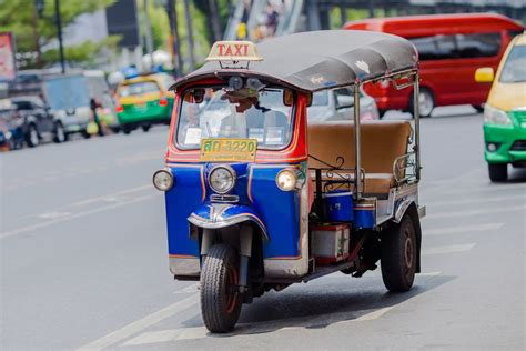 Kolorowy tuk-tuk na azjatyckiej ulicy, pełen pasażerów