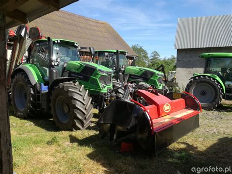 Ciągnik rolniczy Deutz-Fahr 7250 TTV z zamontowaną kosiarką, pracujący na polu