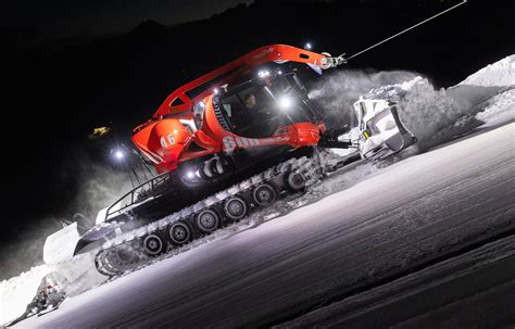 Zdjęcie przedstawiające nowoczesny ratrak PistenBully przygotowujący trasę narciarską w nocy