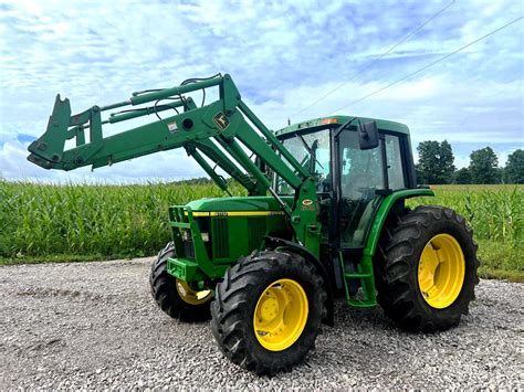 Zdjęcie przedstawiające ciągnik rolniczy John Deere 6110 podczas prac polowych