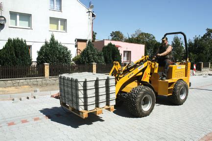 Miniładowarka podczas przewozu palety z kostką brukową
