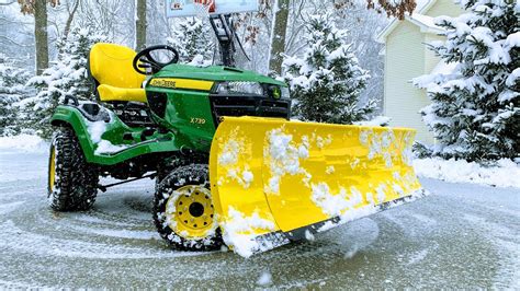 The Stiga snow plow attached to a front-mounted garden tractor, actively plowing snow.