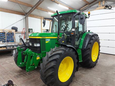 Zdjęcie profilowe ciągnika John Deere 6210 ukazujące jego budowę oraz stanowisko operatora