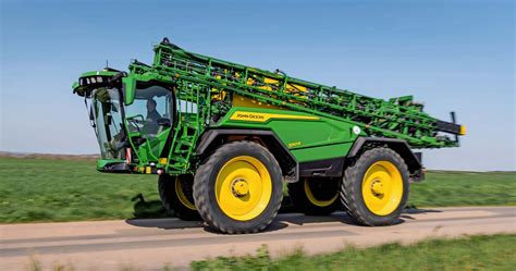 John Deere 500R sprayer being transported on a narrow road