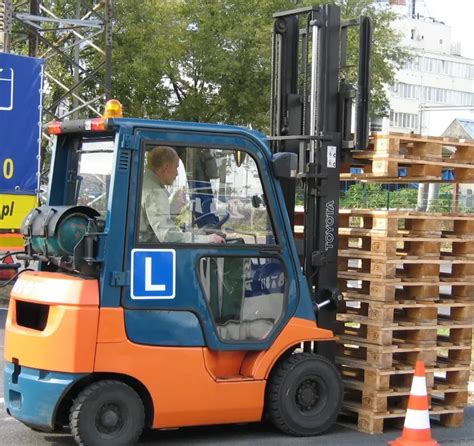 Instruktor szkolący operatora wózka widłowego na placu manewrowym