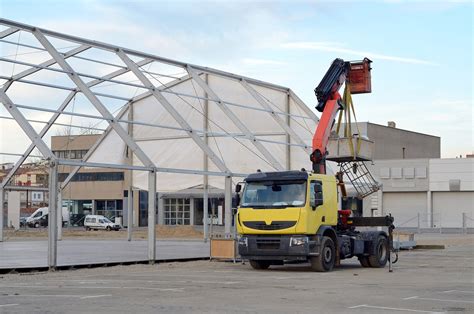 The HDS crane on a truck lifting heavy construction materials with an operator in the foreground