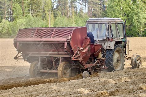 Photo of a potato planter attached to a tractor in a field