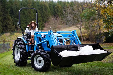 Ciągnik LS Tractor z zamontowanym ładowaczem czołowym w akcji