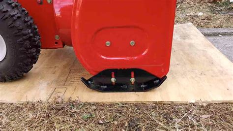 Photo showing the large, treaded tires and adjustable skids of a NAC snow blower