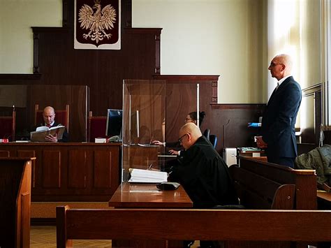 Sądowa sala z osobami na ławie oskarżonych i adwokatami