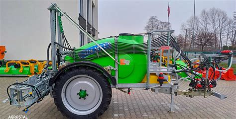 Zdjęcie przedstawiające opryskiwacz polowy marki Tolmet pracujący na polu z rozłożoną belką polową
