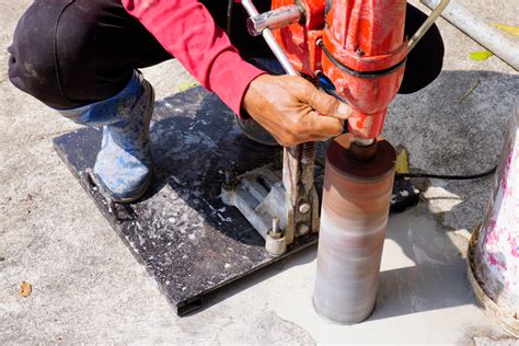 Thematic photo of a person drilling concrete with a handheld drill with water cooling