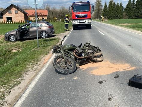 Zniszczony motocykl i ciągnik rolniczy po wypadku, ze służbami ratunkowymi w tle