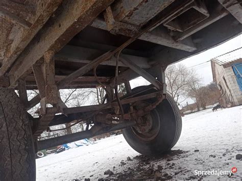 Zdjęcie przedstawiające przyczepę Autosan z otwartą burtą boczną i widocznym mechanizmem wywrotu