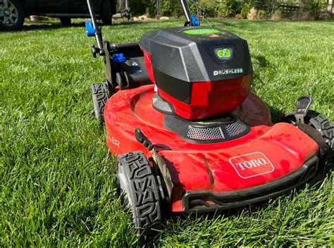 Thematic photo of a powerful gasoline lawn mower on a large green lawn
