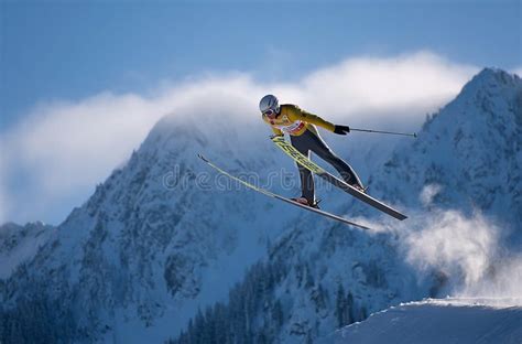 Thematic photo of a ski jumper mid-air against a snowy mountain background