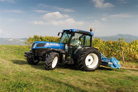Mały ciągnik New Holland z podłączonym osprzętem wykonujący prace polowe