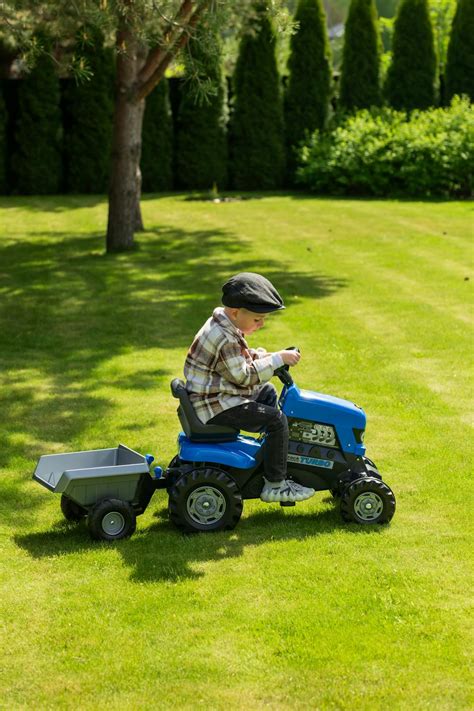 Thematic photo of a child riding a toy tractor outdoors.