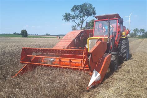 A Bizon Z020 Zagon combine harvester attached to a Ursus tractor in a field