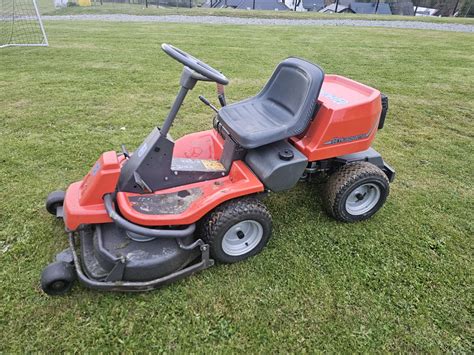 Traktorek ogrodowy Husqvarna na tle zielonego ogrodu