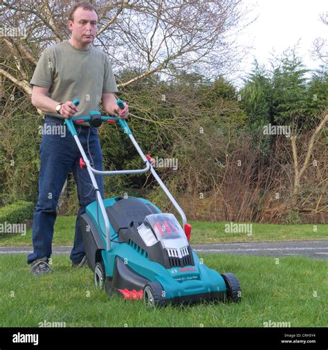 Thematic photo of a person mowing a lawn with a Bosch electric lawnmower.