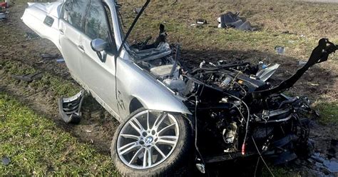 Zniszczony samochód BMW po wypadku, w tle drzewo