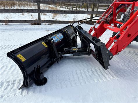 A photo of a versatile compact tractor equipped with a front loader and a snowplow attachment, demonstrating its utility for non-agricultural tasks like material handling and snow removal on paved surfaces, matching the user's specific requirements.
