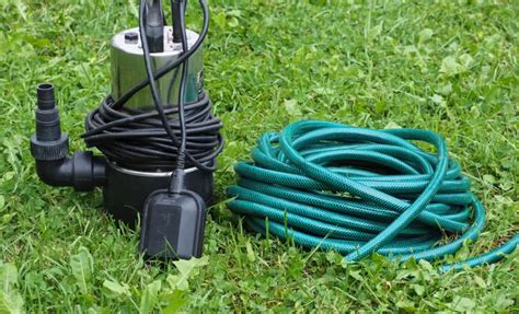 fotografia pompy zanurzeniowej pracującej w beczce z deszczówką, podlewającej ogród