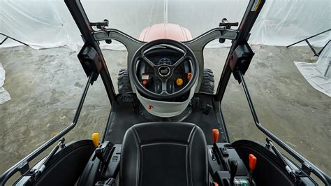 Interior photo of the KIOTI CX2510 cabin, showing ergonomic controls and comfortable seat