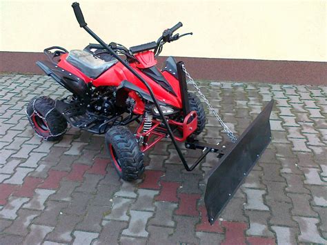 Quad z pługiem do odśnieżania lub koszenia pola, pracujący w gospodarstwie