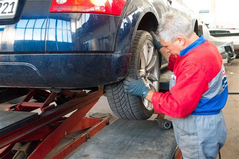 Zdjęcie przedstawiające mechanika naprawiającego minikoparkę