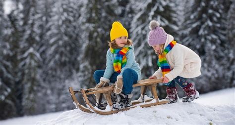 Dziecko bawiące się pługiem śnieżnym Peg Perego zamontowanym na dziecięcym traktorze