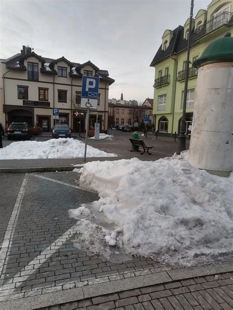 Zaspy śniegu na parkingu, odśnieżane przez maszynę