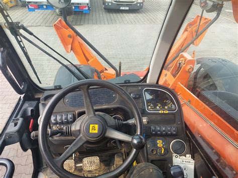 Zdjęcie wnętrza kabiny ładowarki JCB, ilustrujące przestrzeń w obszarze fotela operatora.